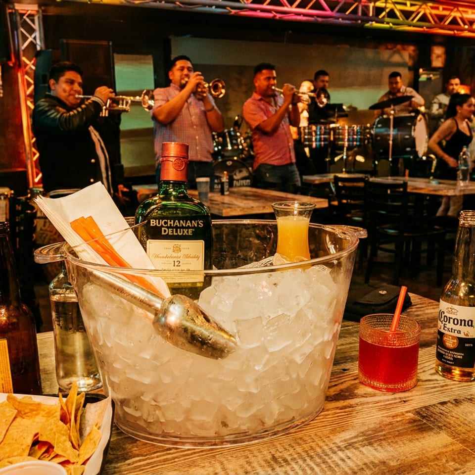 Table with nachos, drinks, and an ice bucket, with a live band playing in the background.